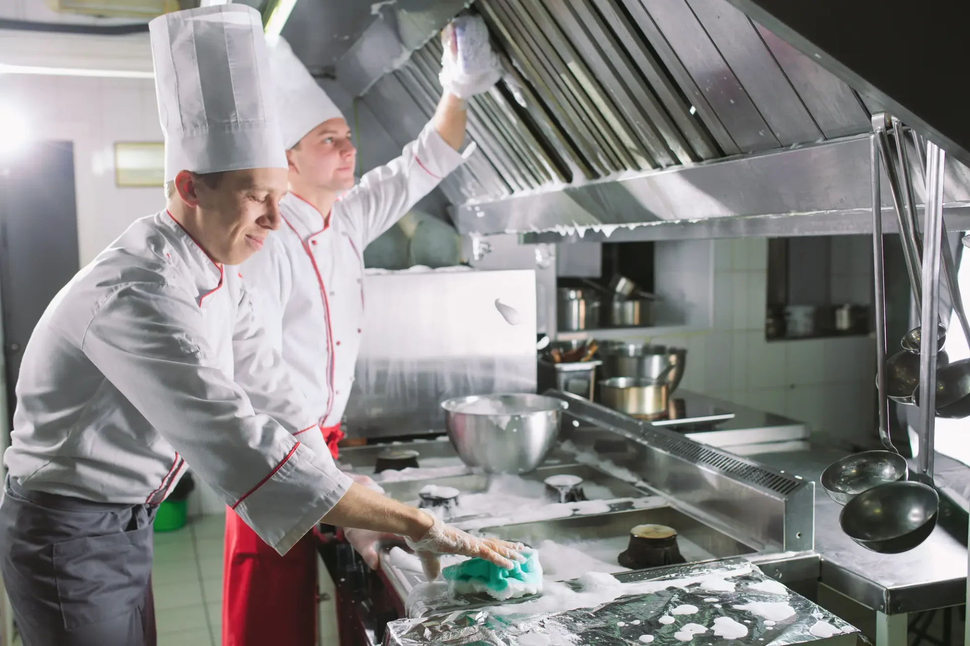 two cooks cleaning kitchen with cleaning detergents
